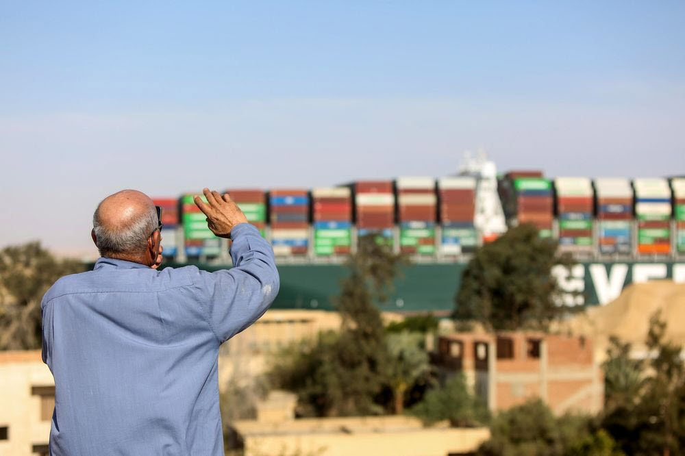 A spectator waves as the Ever Given container ship moves along the Suez Canal towards Ismailia after being freed -energynewsbeat.com