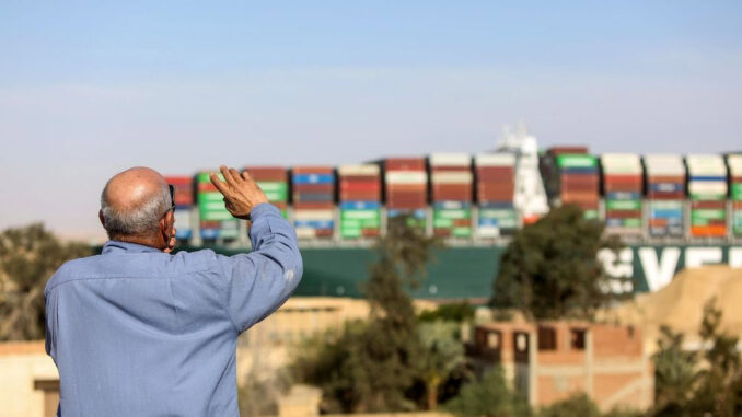 A spectator waves as the Ever Given container ship moves along the Suez Canal towards Ismailia after being freed -energynewsbeat.com