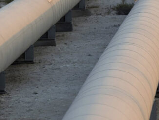 Man on Oil pipeline - photo by Simon Dawson - Bloomberg