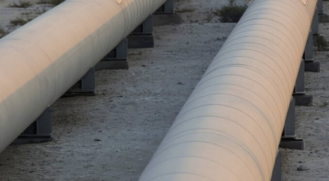 Man on Oil pipeline - photo by Simon Dawson - Bloomberg