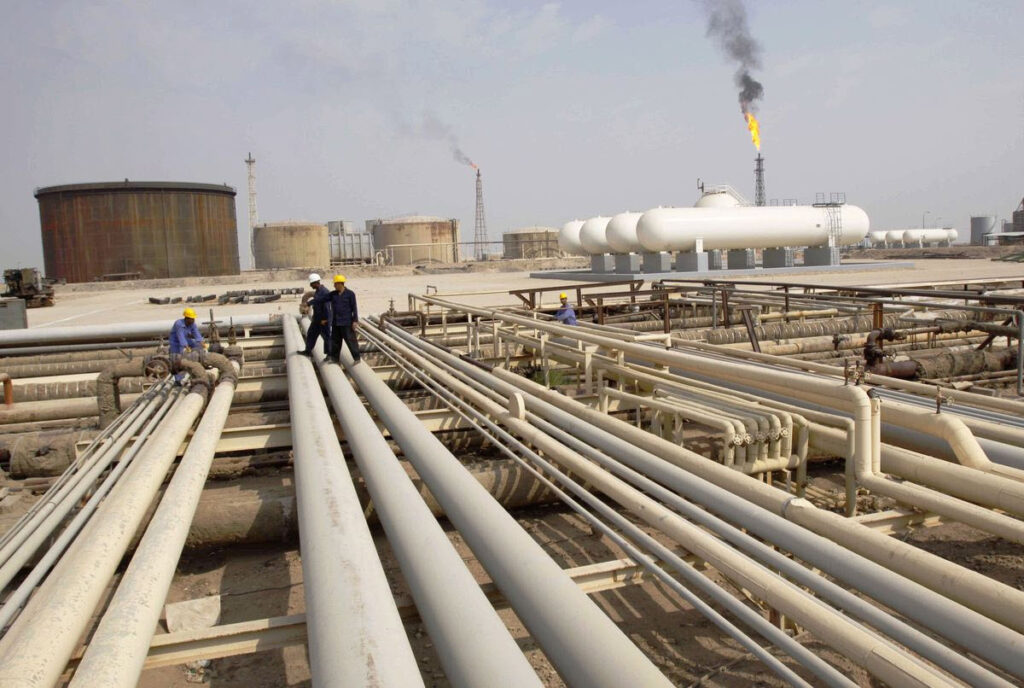 Iraq workers walk on pipelines of an oil refinery - EnergyNewsBeat