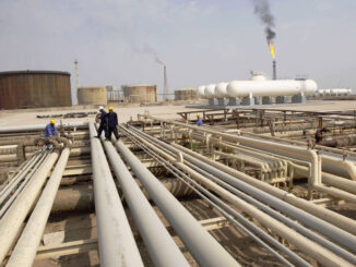 Iraq workers walk on pipelines of an oil refinery - EnergyNewsBeat
